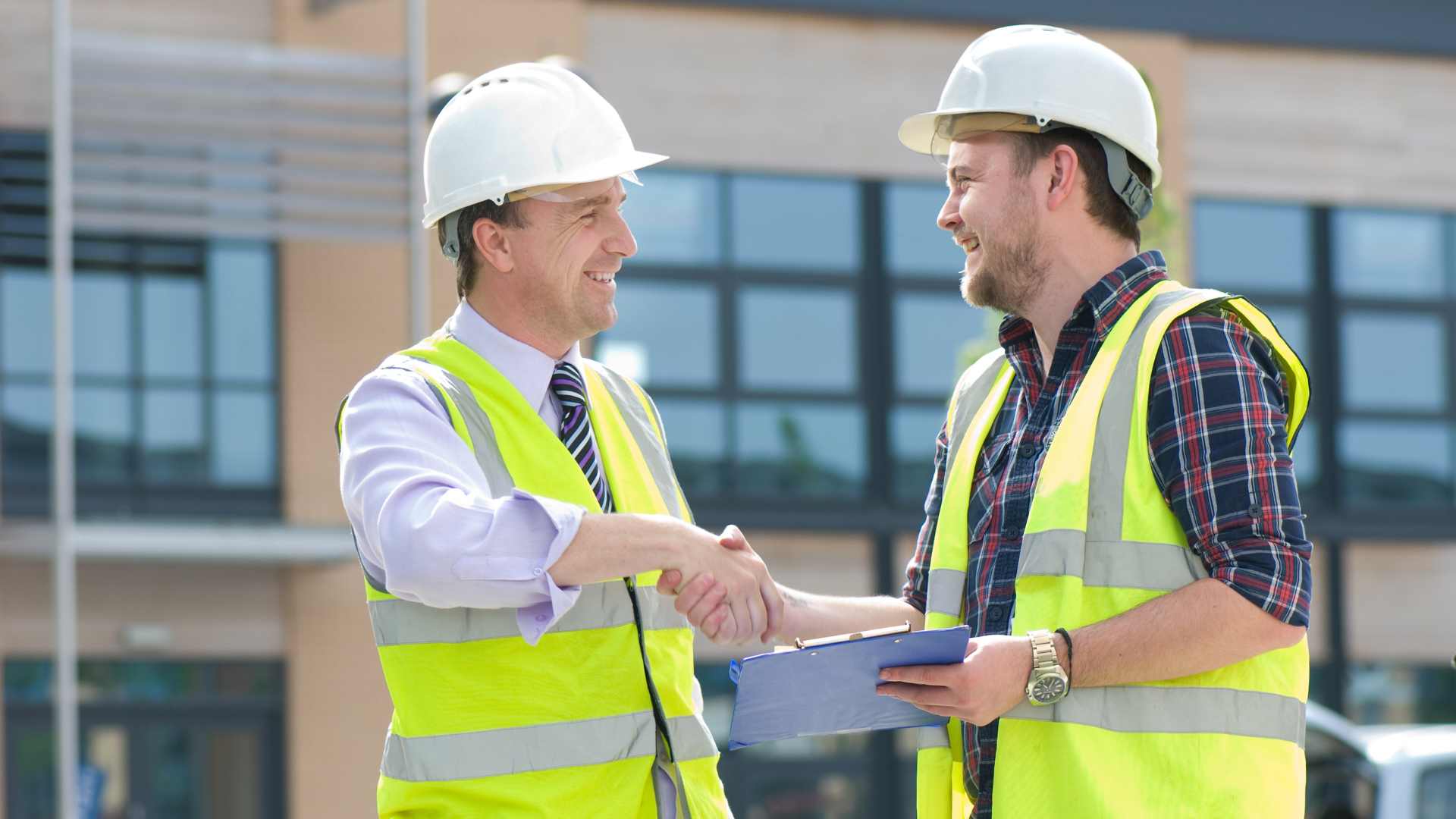 Two builders in hi-vis shaking hands on site