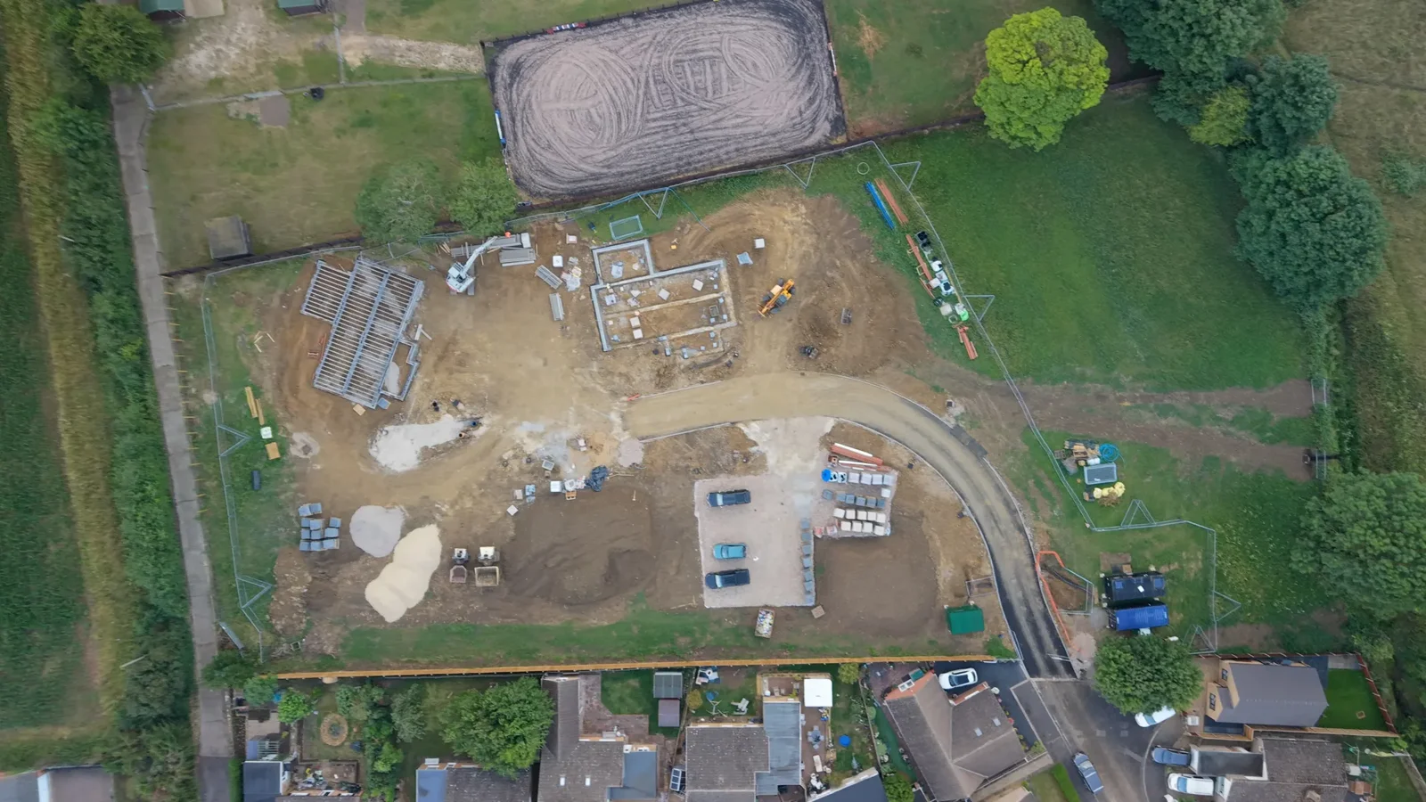 Aerial view of a housing construction site with foundations and a timber roof frame