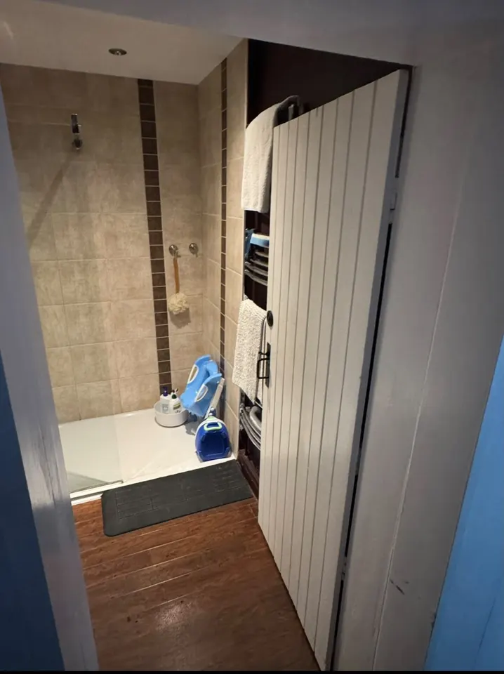 View through the doorway of the completed Ewerby wet room with glass shower screen and wood-effect flooring