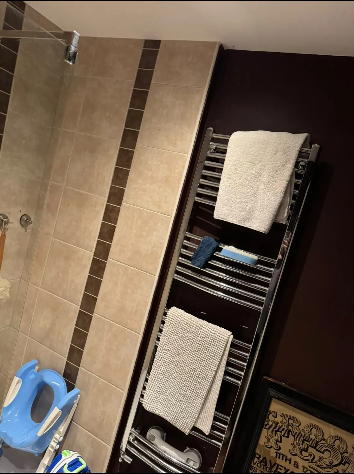 Chrome towel radiator beside beige shower tiles in the completed Ewerby wet room