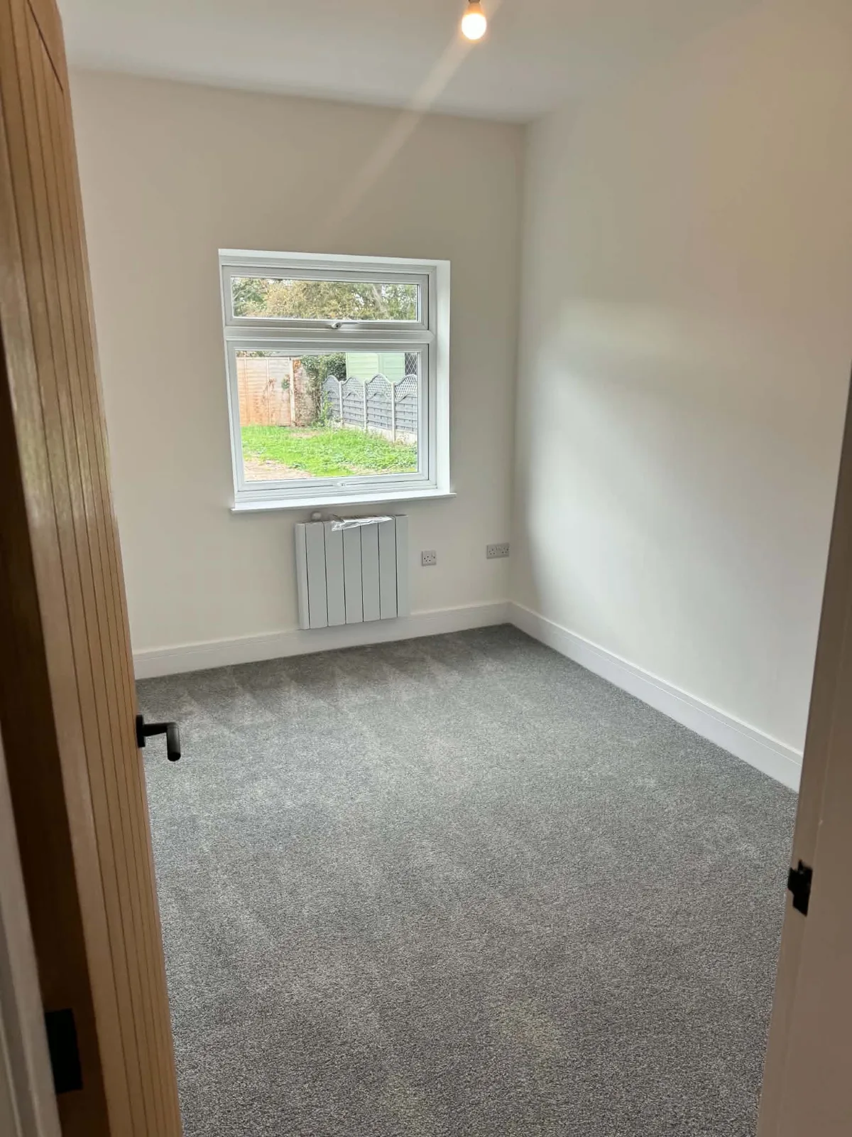 Finished bedroom with grey carpet and a panel radiator in Bassingham