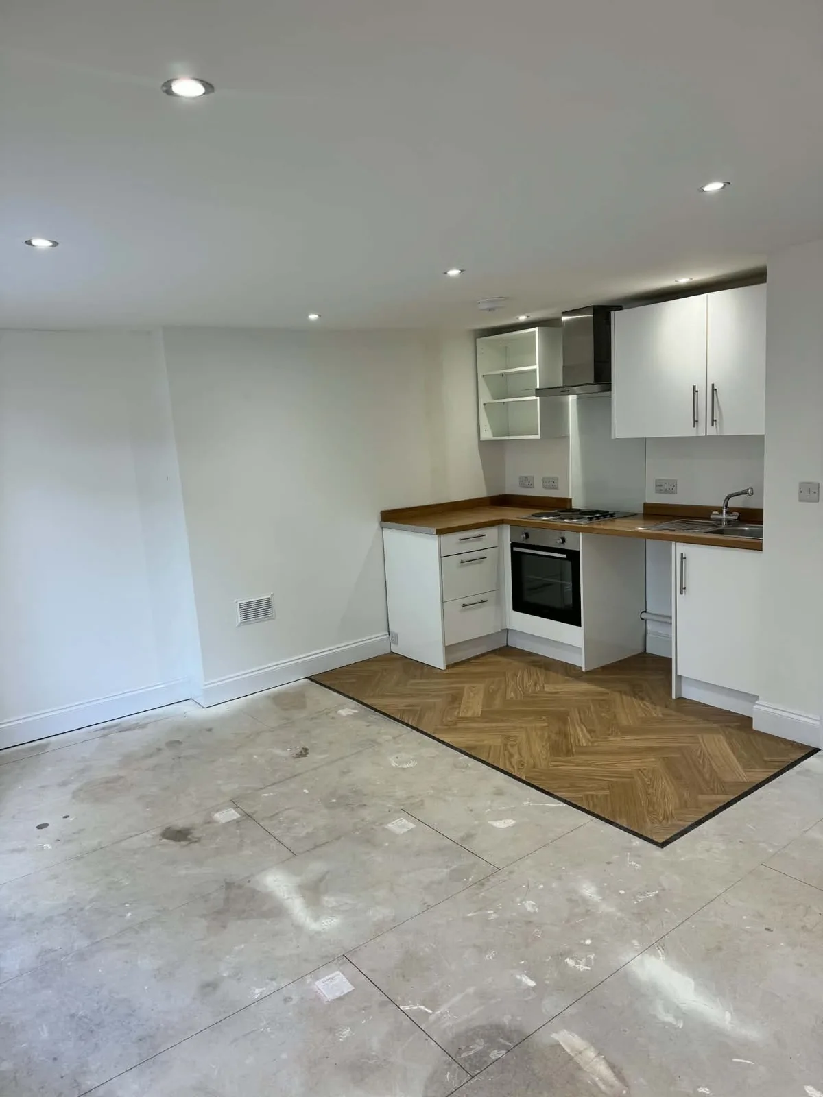White kitchen units and wood-effect kitchen flooring in the decorated Holbeach living area