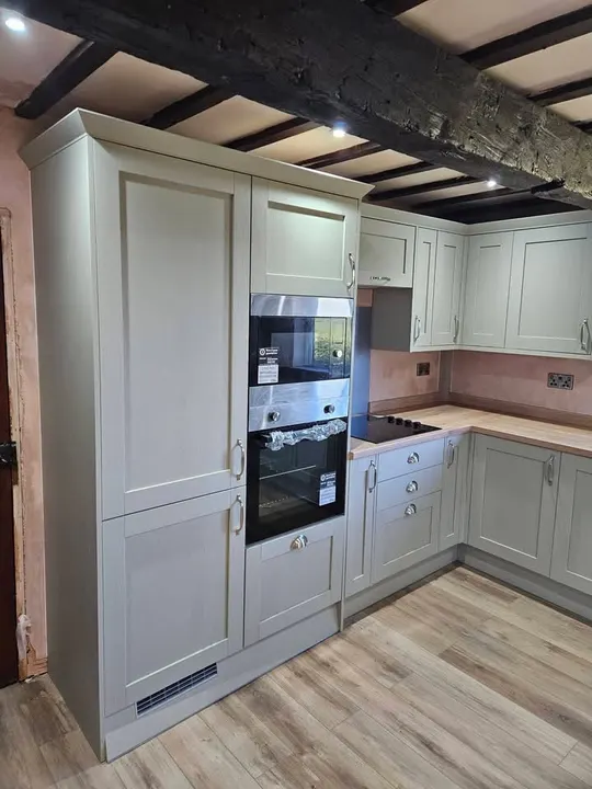 Shaker-style kitchen cabinets and built-in ovens beneath exposed ceiling beams in Sleaford